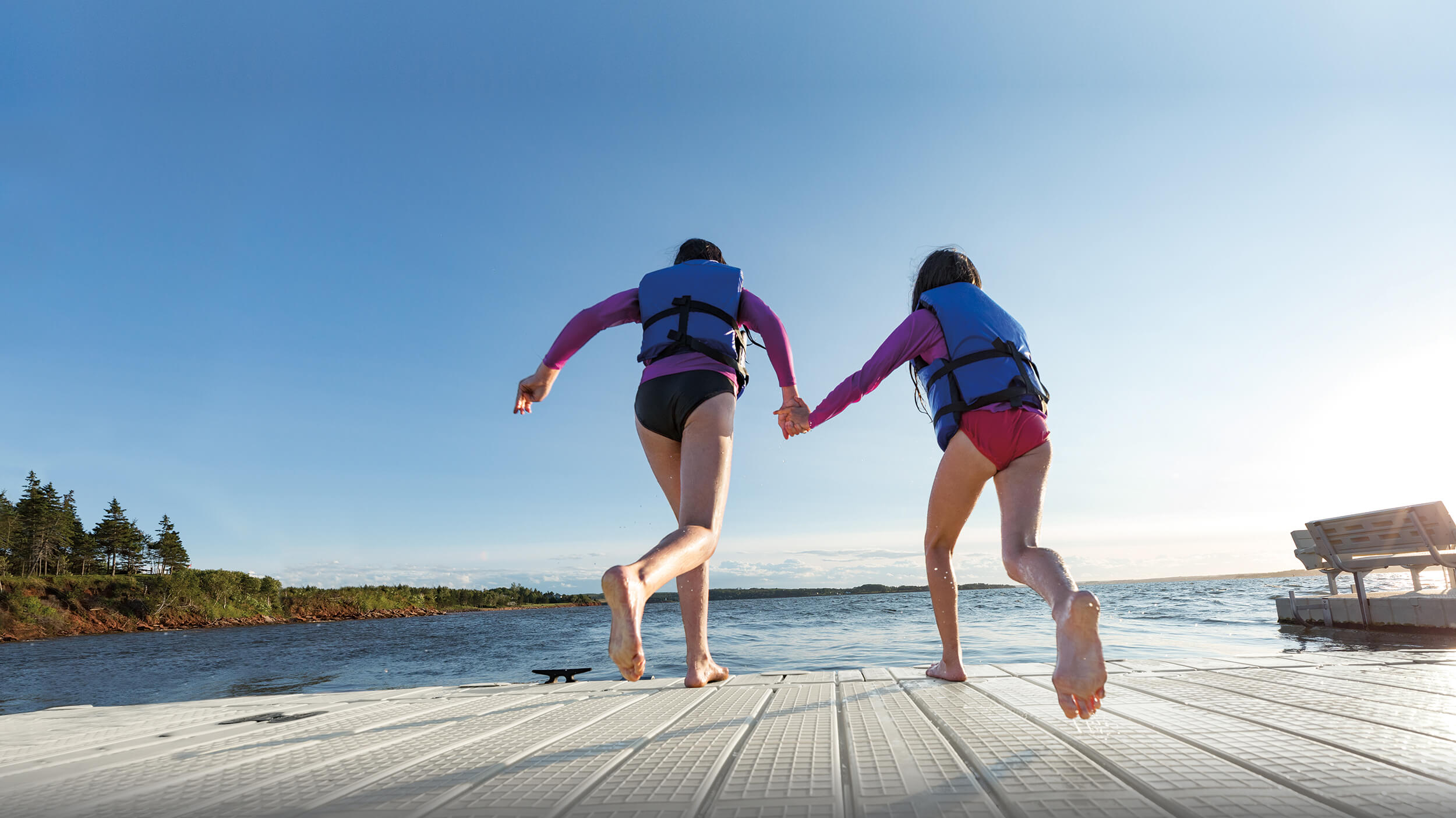 Two children running off of an EZ Dock to jump into the water